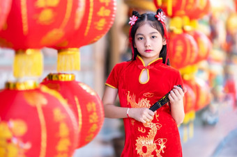 小亚洲女孩穿红色的传统的中国人旗袍和持有范宁和灯笼与的中国人字母<strong>祝福</strong>写《财富》杂志<strong>祝福</strong>赞美装饰为新一年