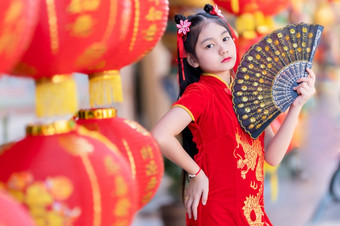 小亚洲女孩穿红色的传统的中国人旗袍和持有范宁和灯笼与的中国人字母祝福写《财富》杂志祝福赞美装饰为新一年