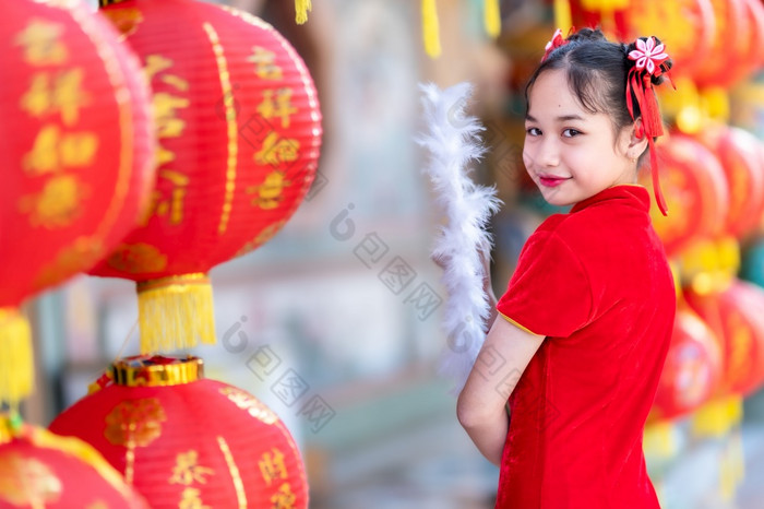 小亚洲女孩穿红色的传统的中国人旗袍和持有范宁和灯笼与的中国人字母祝福写《财富》杂志祝福赞美装饰为新一年