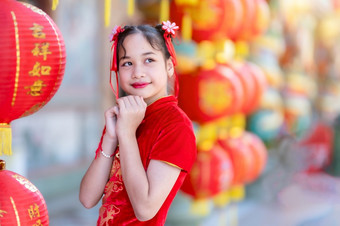 小可爱的亚洲女孩穿传统的中国人旗袍红色的与纸灯笼与的中国人字母祝福写《财富》杂志祝福赞美装饰为中国人新一年