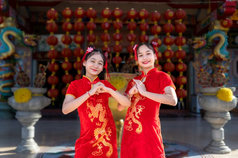 肖像美丽的微笑可爱的小亚洲两个女孩穿红色的传统的中国人旗袍装饰为中国人新一年节日中国人神社
