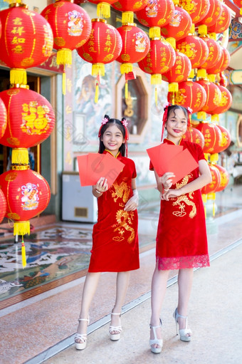 亚洲两个女孩穿红色的传统的中国人旗袍装饰持有红色的信封手和灯笼与的中国人文本<strong>祝福</strong>写《财富》杂志<strong>祝福</strong>为中国人新一年