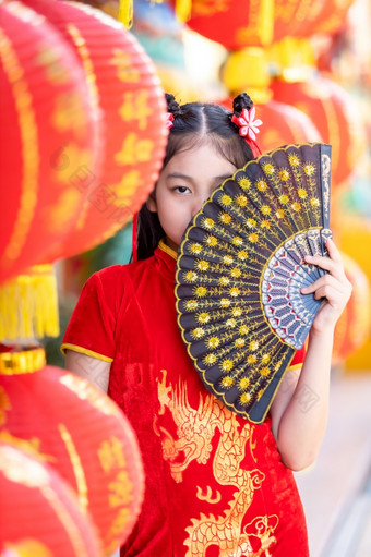 小亚洲女孩穿红色的传统的中国人旗袍和持有范宁和灯笼与的中国人字母<strong>祝福</strong>写《财富》杂志<strong>祝福</strong>赞美装饰为新一年