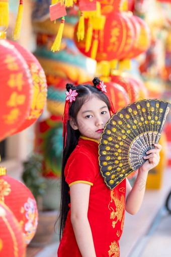 小亚洲女孩穿红色的传统的中国人旗袍和持有范宁和灯笼与的中国人字母<strong>祝福</strong>写《财富》杂志<strong>祝福</strong>赞美装饰为新一年