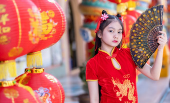 小亚洲女孩穿红色的传统的中国人旗袍和持有范宁和灯笼与的中国人字母<strong>祝福</strong>写《财富》杂志<strong>祝福</strong>赞美装饰为新一年