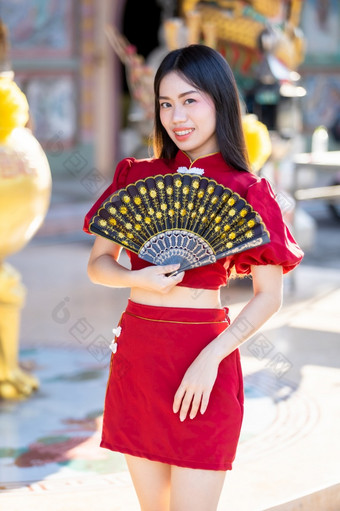 肖像美丽的微笑亚洲年轻的女人穿红色的传统的<strong>中国</strong>人旗袍装饰和持有<strong>中国</strong>人范宁为<strong>中国</strong>人<strong>新</strong>一年节日<strong>中国</strong>人神社泰国