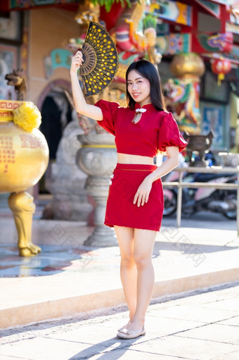 肖像美丽的微笑亚洲年轻的女人穿红色的传统的<strong>中国</strong>人旗袍装饰和持有<strong>中国</strong>人范宁为<strong>中国</strong>人新一<strong>年节</strong>日<strong>中国</strong>人神社泰国
