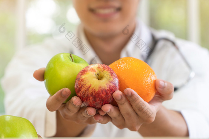 医生营养学家持有新鲜的水果橙色红色的和绿色苹果和微笑诊所健康的饮食概念营养食物处方为好健康水果医学