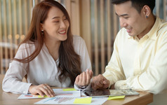 快乐亚洲夫妻微笑后计算收入和费用因为接收利润从投资概念为投资规划和金融规划为的家庭