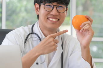 医生营养学家持有橙<strong>色和</strong>点你的手指的橙<strong>色和</strong>微笑诊所健康的饮食概念营养食物处方为好健康水果医学