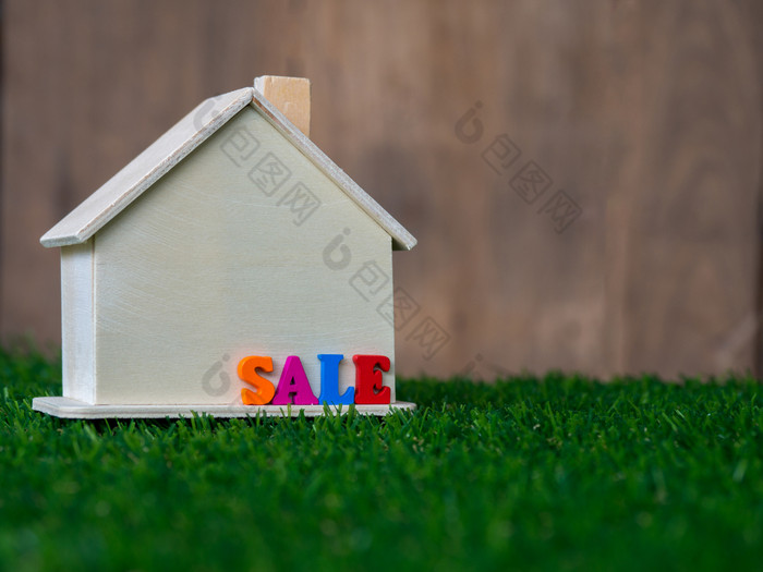 木房子模型放置绿色草坪上和色彩斑斓的文本出售的房子生态房子概念