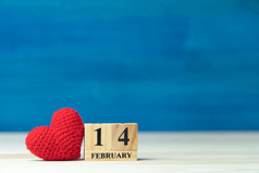 情人节一天概念手使纱红色的心旁边木块日历集情人节日期2月木表格和蓝色的背景