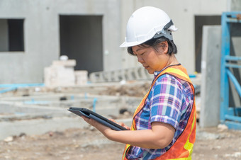 肖像亚洲女人建设工程师工人与头盔头使用平板电脑而站建设网站建筑网站的地方背景建设概念