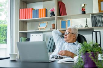 亚洲上了年纪的男人。坐着前面移动PC电脑坐着回来他的椅子和放松的上了年纪的可以仍然工作和创建<strong>句子</strong>为社会病毒检疫