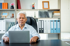 快乐亚洲上了年纪的男人。坐着前面移动PC电脑概念的上了年纪的可以仍然工作和创建句子为社会病毒检疫