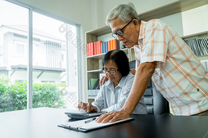 高级亚洲夫妇使用的计算器和文书工作桌子上首页计算费用和收入和储蓄后退休概念金融规划和投资为退休人员