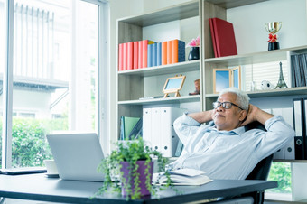 亚洲上了年纪的男人。坐着前面移动PC电脑坐着回来他的椅子和放松的上了年纪的可以仍然工作和创建句子为社会病毒检疫