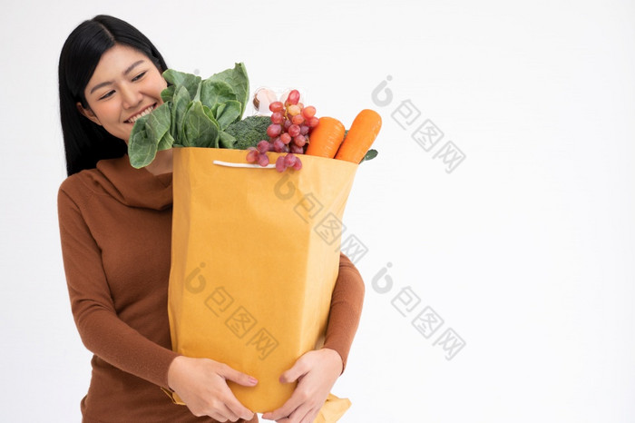 快乐亚洲女人微笑和携带购物纸袋后的快递从的杂货店来了交付他的货物首页概念超市交付为新生活方式