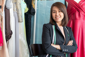 快乐年轻的亚洲女人裁缝时尚设计师检查为完成为西装和衣服展厅概念成功年轻的企业家的时尚业务
