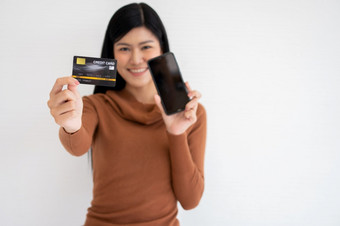 快乐亚洲女人持有卡信贷和智能手机为移动银行的互联网概念新生活方式和融资技术