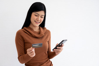 快乐亚洲女人持有卡信贷和智能手机为移动银行的互联网概念<strong>新生活方式</strong>和融资技术