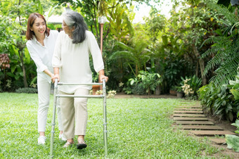 <strong>老</strong>上了年纪的亚洲女人使用沃克和走的后院与她的女儿概念快乐退休与哪从照顾者和储蓄和高级健康保险