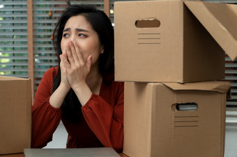 伤心亚洲女人包装物品纸板盒子和哭的桌子上的办公室后被裁员和失业概念影响的经济经济低迷和管理的失败