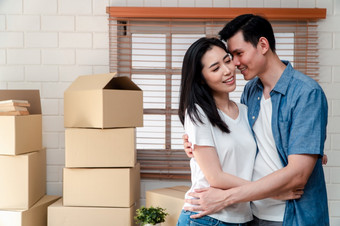 微笑年轻的亚洲快乐夫妇拥抱的男朋友与纸板盒子移动一天他们的新首页后购买真正的房地产概念开始新生活为新结婚了夫妇