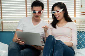 快乐年轻的夫妇穿眼镜看笔记本和在一起看电影概念技术为方便幸福后婚姻