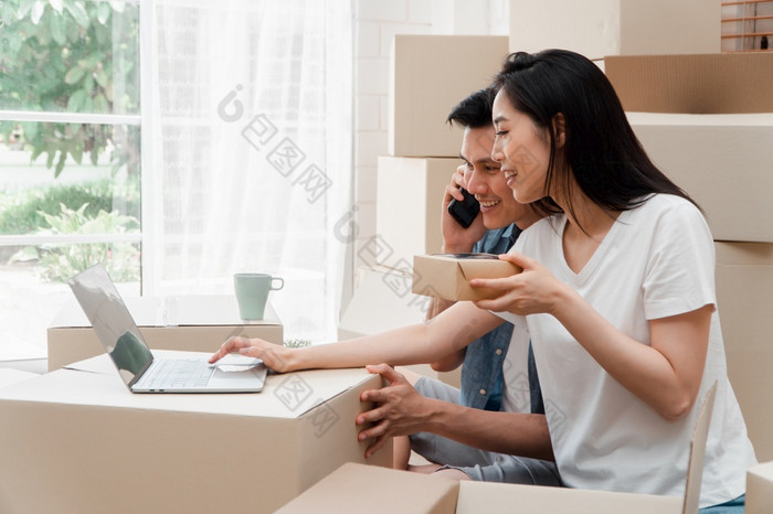 微笑年轻的亚洲快乐夫妇使用移动PC为首页装饰的想法移动一天他们的新首页后购买真正的房地产概念开始新生活为新结婚了夫妇