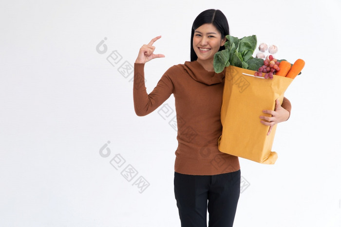 快乐亚洲女人微笑和开放的棕榈的手和携带购物袋后的快递从杂货店来了交付首页概念超市交付为新生活方式