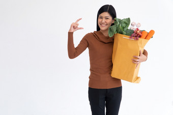快乐亚洲女人微笑和开放的棕榈的手和携带购物袋后的快递从杂货店来了交付首页概念超市交付为新生活方式