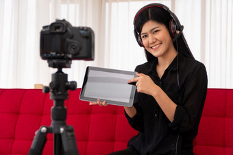 视频博客亚洲女人博主影响者坐着的沙发首页和记录视频博客为教学和教练她的学生订阅者概念的内容创造者在线为<strong>新生活方式</strong>