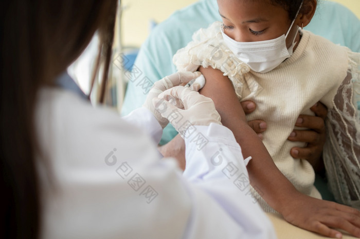 亚洲医生用户注射器针为注射接种疫苗非洲美国孩子们是被科维德接种疫苗为预防冠状病毒和流感概念免疫接种从接种