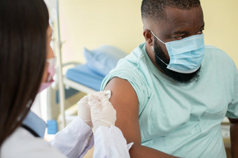 亚洲医生用户注射器针为注射接种疫苗非洲美国被科维德接种疫苗为预防冠状病毒和流感概念免疫接种从接种