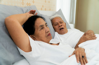 老亚洲女人铺设开放她的眼睛床上旁边她的丈夫谁鼾声和使<strong>噪音</strong>婚姻问题
