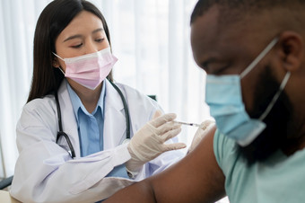 亚洲医生用户注射器针为注射接种疫苗非洲美国被科维德接种疫苗为预防冠状病毒和流感概念免疫接种从接种