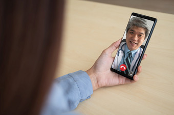 亚洲医生治疗师帮助<strong>缓解压力</strong>和提供知识和理解关于办公室并发症状病人视频会议调用在线生活说话远程首页智能手机