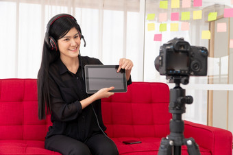 视频博客亚洲女人博主影响者坐着的沙发首页和记录视频博客为教学和教练她的学生订阅者概念的内容创造者在线为<strong>新生活方式</strong>
