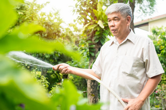 快乐和微笑亚洲老上了年纪的男人。浇水植物和花<strong>为爱</strong>好后退休首页概念快乐生活方式和好健康<strong>为</strong>老年人