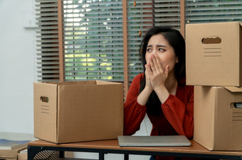 伤心亚洲女人包装物品纸板盒子和哭的桌子上的办公室后被裁员和失业概念影响的<strong>经济经济</strong>低迷和管理的失败