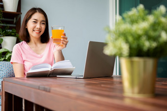 中年人了亚洲女人阅读书和持有橙色汁<strong>玻璃</strong>的<strong>首页</strong>概念健康哪和吃为健康的