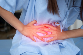不开心亚洲病人女人坐着的医院床上和持有胃痛苦腹部疼痛那来了从月经腹泻消化不良病和医疗保健概念