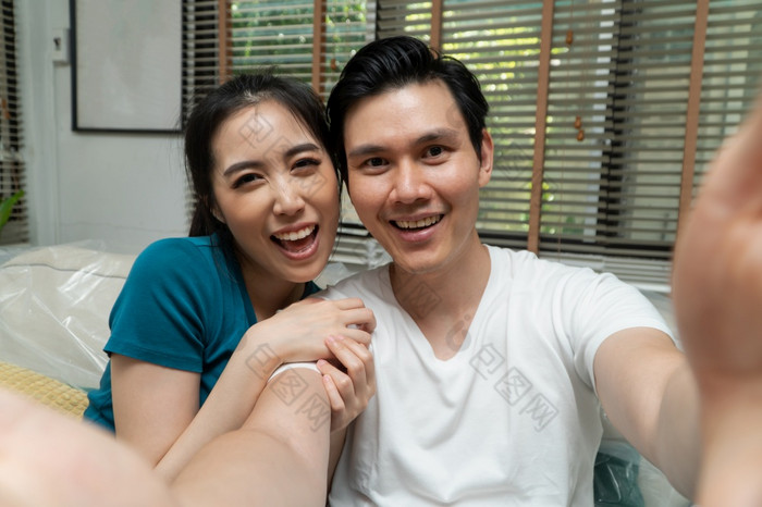 亚洲夫妇持有智能手机和视频会议与家庭后的移动新首页的第一个一天概念搬迁和换位为开始新生活