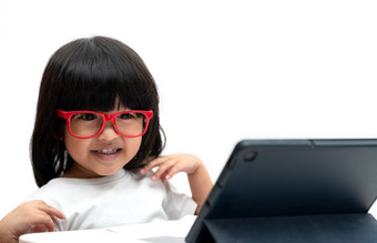 小亚洲学龄前儿童女孩穿红色的眼镜和使用平板电脑白色背景亚洲女孩会说话的和学习与视频调用与平板电脑教育概念为学校孩子们