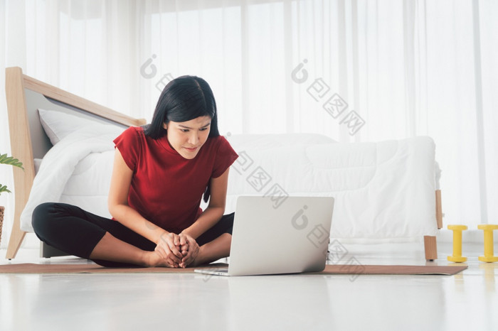 肖像健康的年轻的亚洲女人练习瑜伽练习坐着的卧室和学习在线移动PC首页概念锻炼和放松技术为新正常的生活方式
