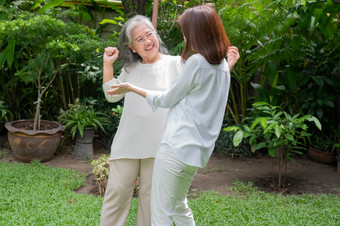 <strong>老</strong>上了年纪的亚洲女人和跳舞的后院与她的女儿概念快乐退休与哪从照顾者和储蓄和高级健康保险快乐家庭