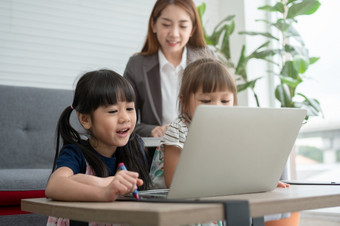亚洲妈妈。与她的两个孙子有有趣的和玩教育游戏在线与数字电脑移动PC首页的生活房间概念在线教育和有爱心的从父母