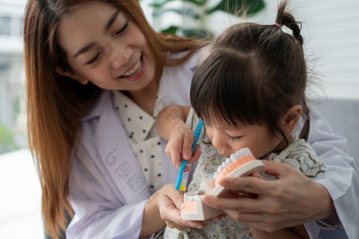 亚洲女牙医教学可爱的小女孩刷牙牙齿与牙刷和口腔学家告诉女孩孩子关于口服卫生牙科诊所教育和预防蛀牙概念