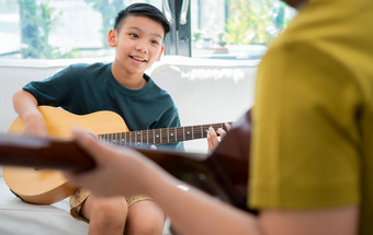 亚洲男孩玩吉他与父亲<strong>的生活</strong>房间为教学他儿子玩吉他感觉欣赏和鼓励概念快乐家庭<strong>学习</strong>和有趣<strong>的生活</strong>方式爱家庭关系